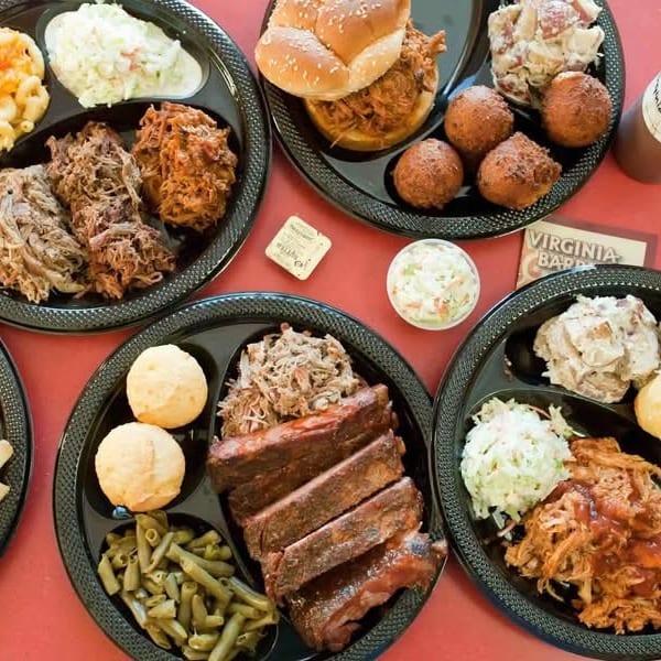 Multiple plates of Virginia Barbecue with pulled pork, ribs, mac and cheese, coleslaw, and hush puppies.