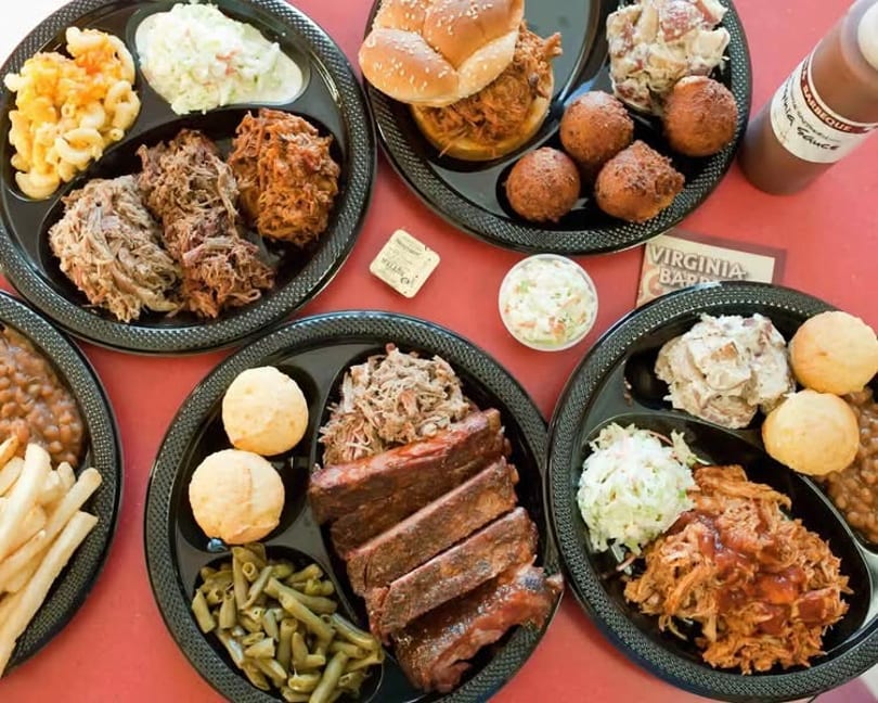 Multiple plates of Virginia Barbecue with pulled pork, ribs, mac and cheese, coleslaw, and hush puppies.